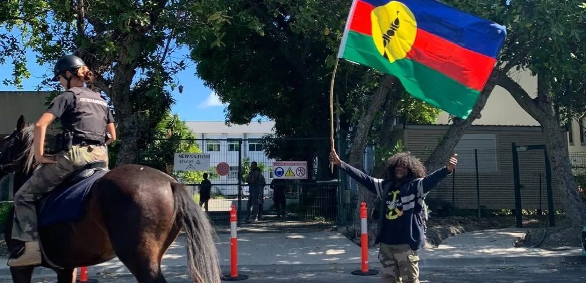 Un habitant agite le drapeau kanak au passage d’un agent de la gendarmerie montée dans le sillage des manifestations contre le dégel du corps électoral. Nouvelle-Calédonie, 11 mai 2024. Photo : DR Un habitant agite le drapeau kanak au passage d’un agent de la gendarmerie montée dans le sillage des manifestations contre le dégel du corps électoral. Nouvelle-Calédonie, 11 mai 2024. Photo : DR