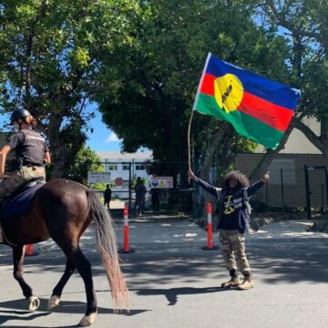 Un habitant agite le drapeau kanak au passage d’un agent de la gendarmerie montée dans le sillage des manifestations contre le dégel du corps électoral. Nouvelle-Calédonie, 11 mai 2024. Photo : DR Un habitant agite le drapeau kanak au passage d’un agent de la gendarmerie montée dans le sillage des manifestations contre le dégel du corps électoral. Nouvelle-Calédonie, 11 mai 2024. Photo : DR