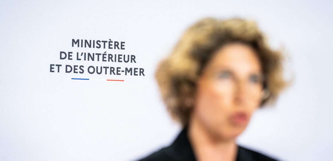 Paris le 16 avril 2024. Photographie par Xose Bouzas / Hans Lucas / AFP. Conférence de presse au sujet de la lutte contre l’immigration irrégulière et la délinquance à Mayotte, au ministère de l’Intérieur et des Outre-mer. Près d’un an après le lancement de l’opération Wuambushu, la ministre déléguée chargée des Outre-mer, lance une nouvelle opération d’ampleur pour lutter contre l’immigration irrégulière, la délinquance et l’habitat illégal à Mayotte. Illustration du logo du ministère de l’Interieur et des Outre mer lors de la prise de parole de Marie Guevenoux, ministre déléguée auprès du ministre de l’Interieur et des Outre-mer, chargée des Outre-mer, floue au premier plan. Paris le 16 avril 2024. Photographie par Xose Bouzas / Hans Lucas / AFP. Conférence de presse au sujet de la lutte contre l’immigration irrégulière et la délinquance à Mayotte, au ministère de l’Intérieur et des Outre-mer. Près d’un an après le lancement de l’opération Wuambushu, la ministre déléguée chargée des Outre-mer, lance une nouvelle opération d’ampleur pour lutter contre l’immigration irrégulière, la délinquance et l’habitat illégal à Mayotte. Illustration du logo du ministère de l’Interieur et des Outre mer lors de la prise de parole de Marie Guevenoux, ministre déléguée auprès du ministre de l’Interieur et des Outre-mer, chargée des Outre-mer, floue au premier plan.